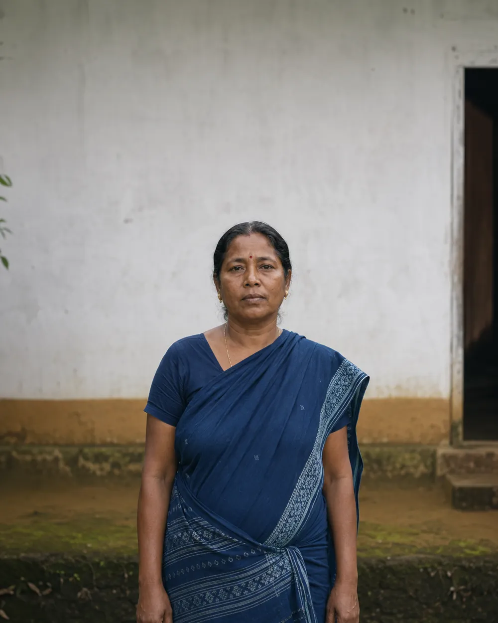 Portrait of a woman standing outside her home.